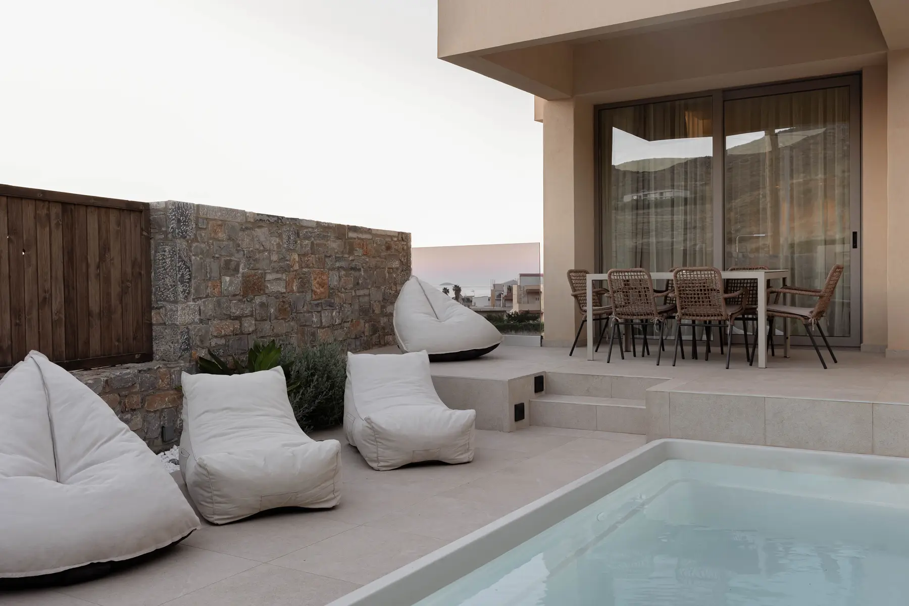 Deluxe Suite terrace at dusk with beanbag loungers, outdoor dining and pool