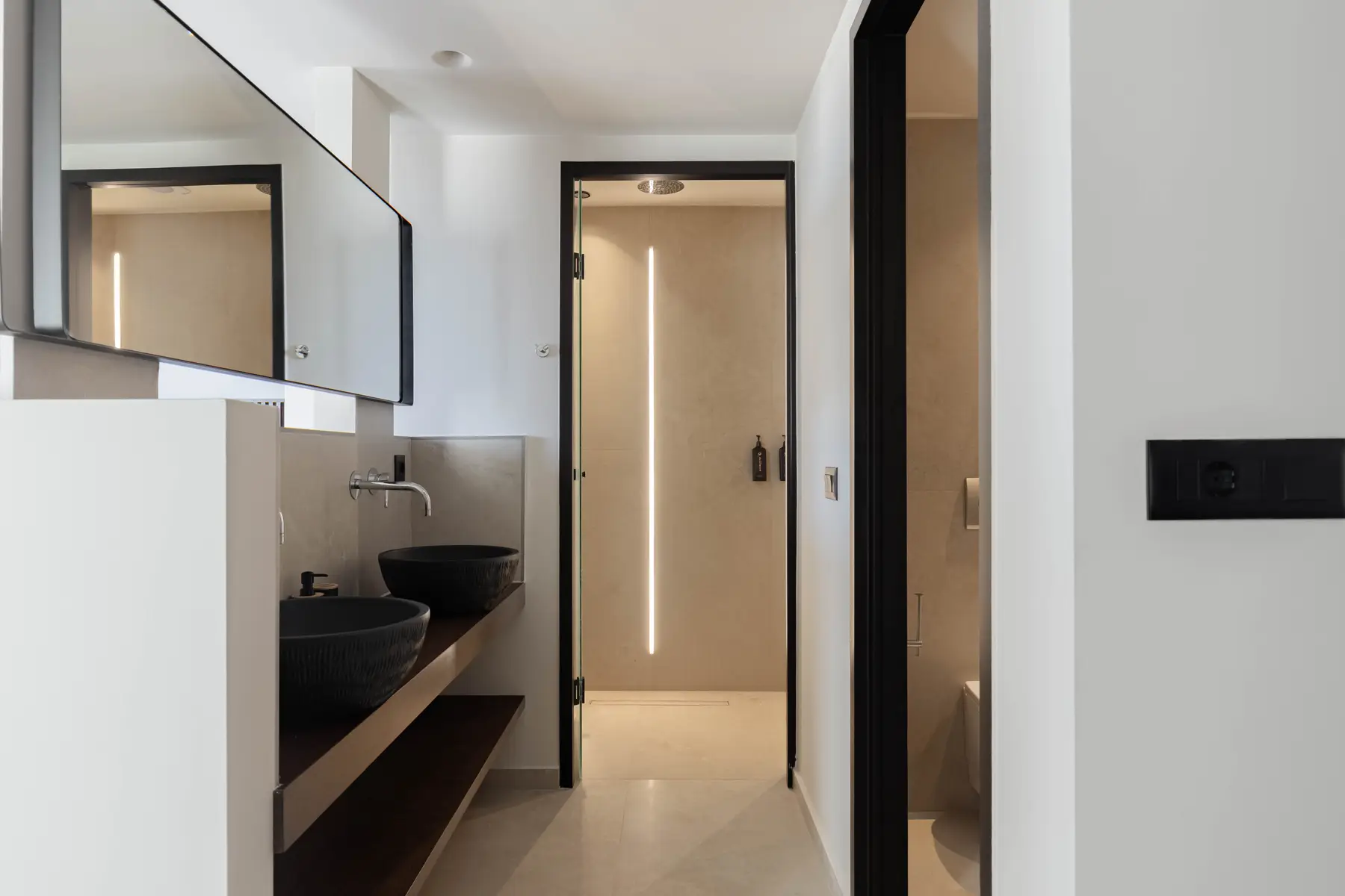 Double black-basin vanity with the walk-in shower beyond
