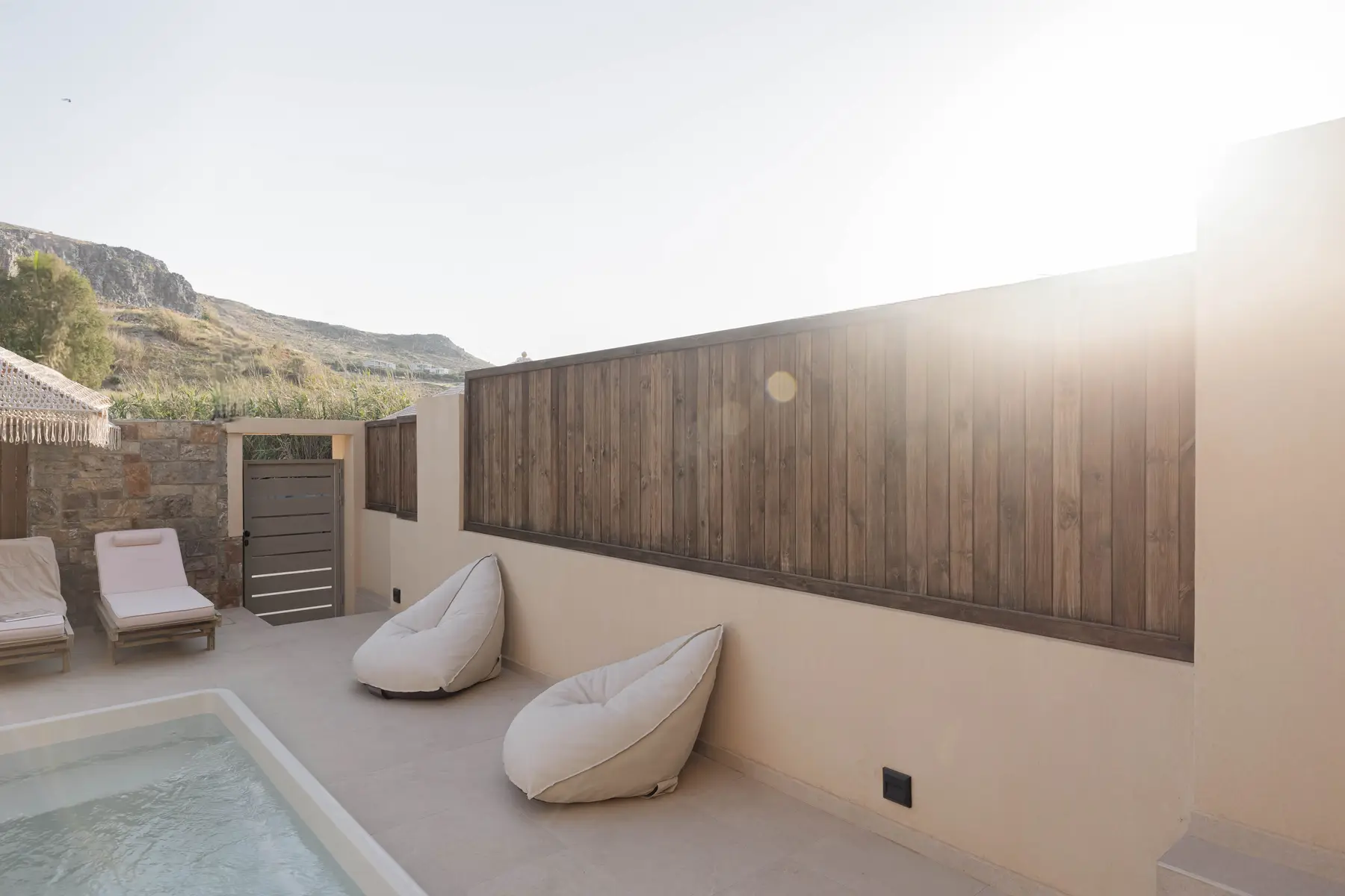 Evening sun over the poolside loungers and timber wall