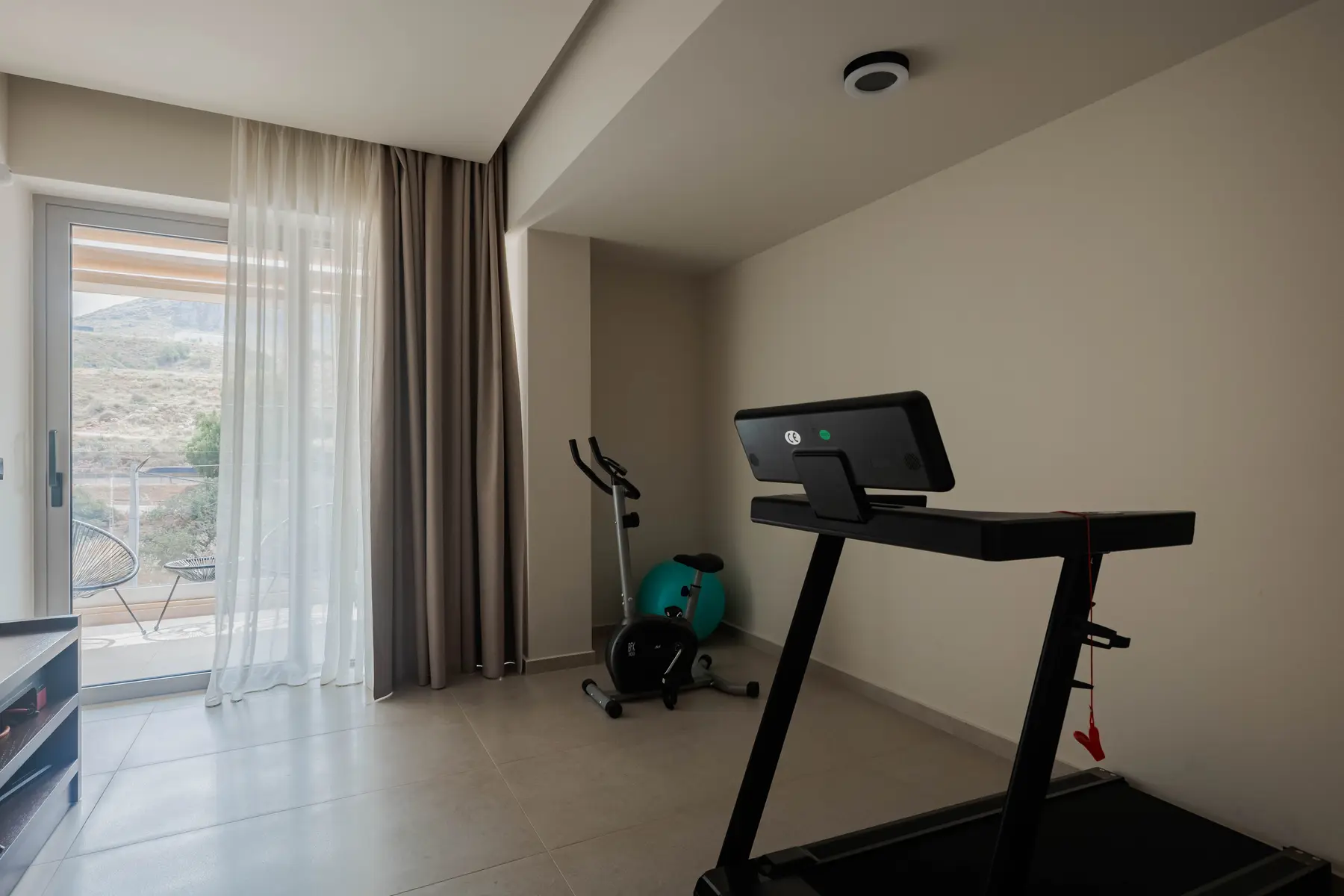 Private gym of the Two-Bedroom Suite with treadmill and exercise bike beside the balcony